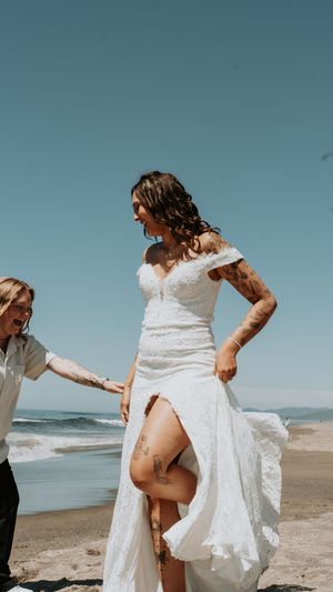 Playful moments captured on a beach with flowing white wedding dress.