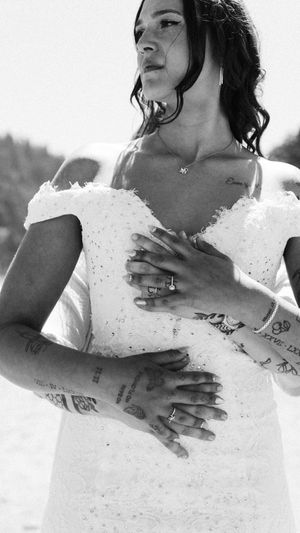 Close-up sequence showing hands with tattoos against a white lace wedding dress.