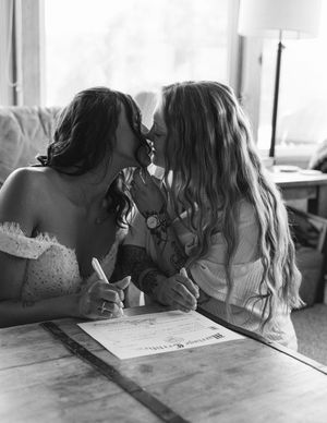 Black and white photo of two people signing documents together.
