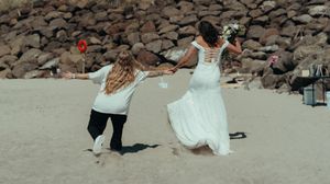 Wedding celebration scene on a rocky beach with decorative stone arrangements.
