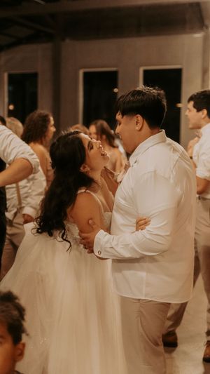 Wedding reception dance floor with couples dancing in white and formal attire.