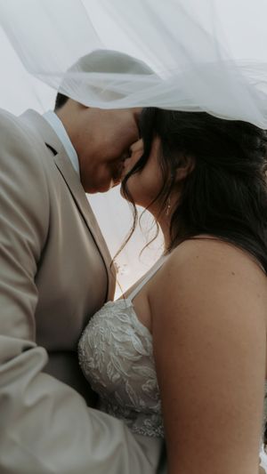 Intimate wedding couple sharing a tender kiss in a romantic close-up shot with soft lighting.