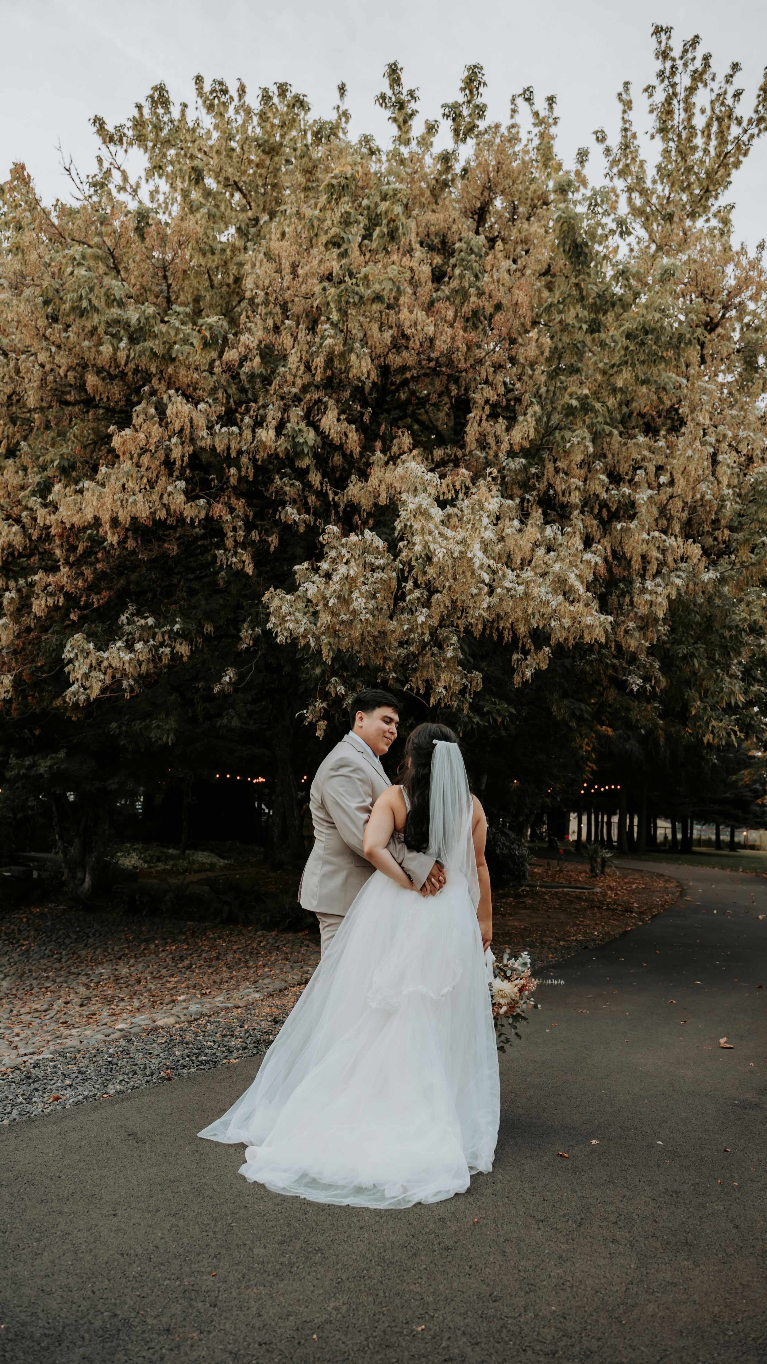 Romantic outdoor wedding portraits at sunset with trees creating a natural backdrop.