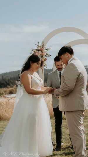 A romantic first look moment between a couple in a field with mountains in the background.