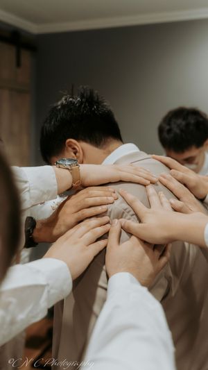 People join hands in a circle during a prayer or blessing moment at what appears to be a wedding ceremony.