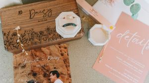Wedding stationery featuring wooden box, brown envelope and blush pink invitation with floral details.