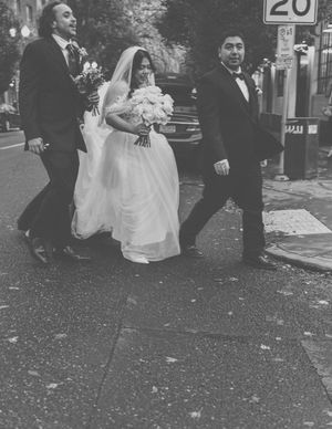 A black and white wedding party walks together on a street with a speed limit sign visible.