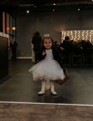 A sequence of photos showing a small child in a white tulle dress twirling and dancing on a dark floor with string lights.