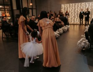 A wedding ceremony in progress with string lights creating a romantic backdrop and guests seated in rows.