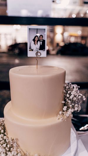 Simple white wedding cake decorated with delicate baby's breath flowers and topped with small photo prints.