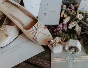 Flat lay composition of wedding stationery with elegant invitations, envelopes and dried floral elements on white surface.