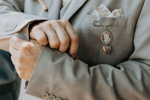 Close-up shot of hands adjusting a gray suit jacket button while wearing formal attire.