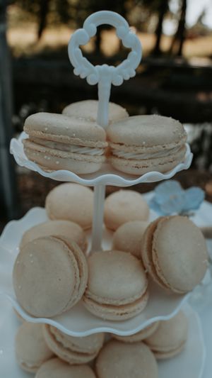 White macarons elegantly displayed on a tiered dessert stand at a wedding reception.