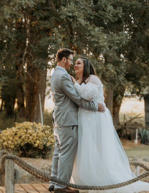 A joyful couple shares an intimate moment on a wooden bridge during their outdoor wedding.