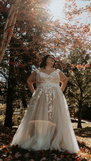 White tulle flower girl dresses twirl in autumn sunlight beneath trees with orange leaves.