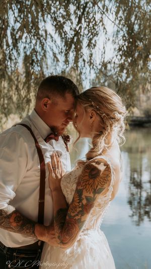 A romantic wedding photo series by a lake showing intimate moments between a couple in white attire.