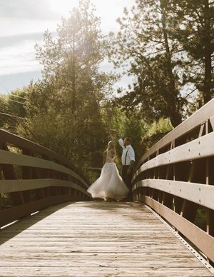 A wooden footbridge path extends through trees and foliage in a natural outdoor setting.