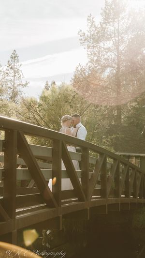 Silhouettes of a couple sharing romantic moments on a wooden bridge during golden hour.