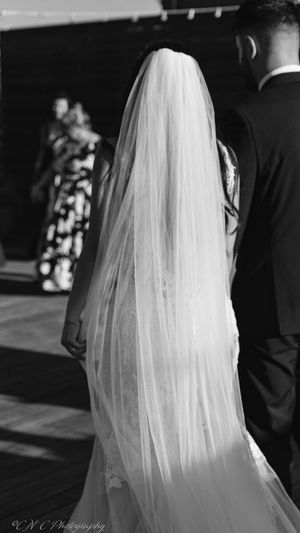 Close-up detail of a flowing white wedding veil against a dark background.