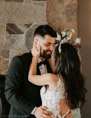 A tender moment between newlyweds against a stone wall backdrop.