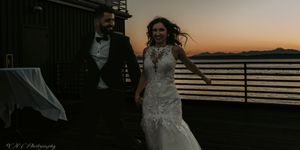 Silhouetted figures dancing on an oceanfront deck against a dramatic sunset sky.