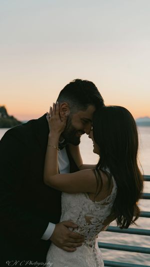 Silhouetted couple sharing an intimate moment at sunset on a waterfront deck.
