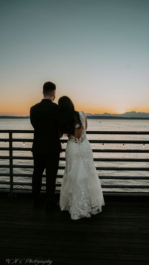 Couple sitting together on wooden pier overlooking sunset waters.