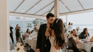 An intimate indoor wedding reception setup with white decor and natural lighting.