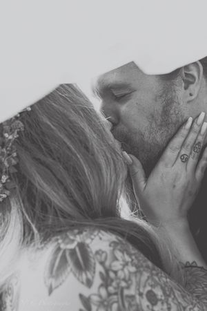 A black and white close-up photograph of a romantic wedding kiss.