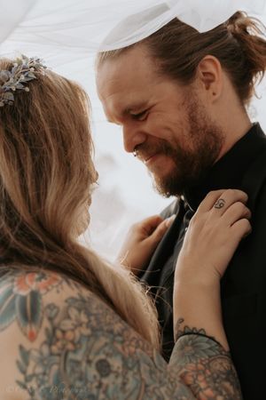 An intimate wedding moment captured between a couple sharing a tender smile under a veil.