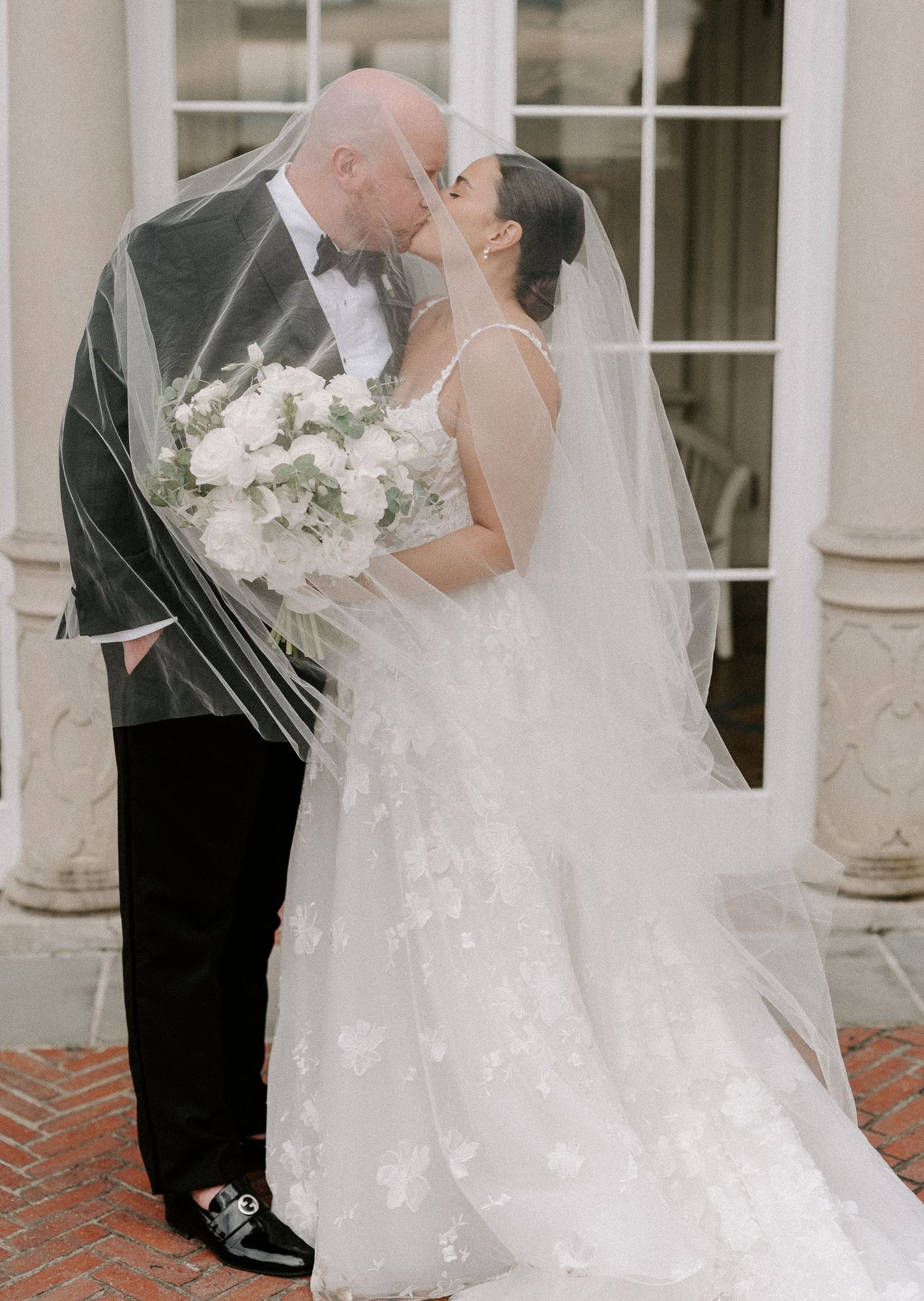 Elegant wedding portraits with flowing veil against classic architectural backdrop.
