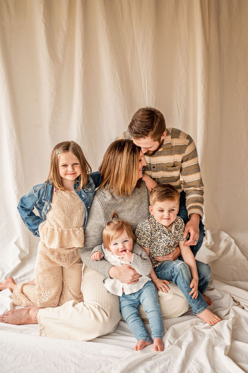 A sweet family moment captured in a series of candid photos on white bedding showing playful interaction and cuddles.