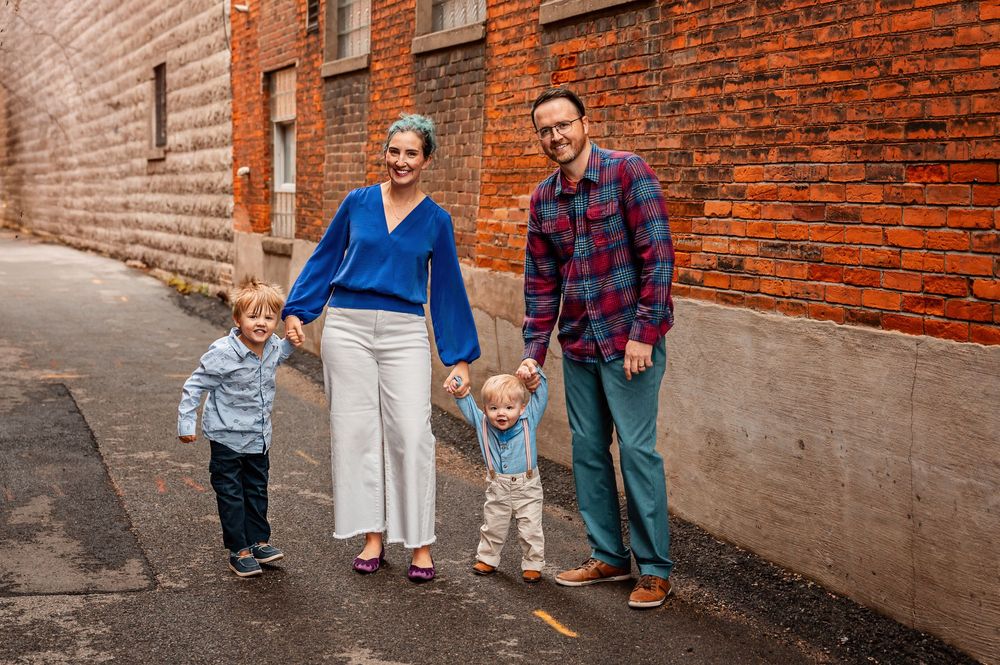 A family poses together against a rustic brick wall background during an outdoor photo session.