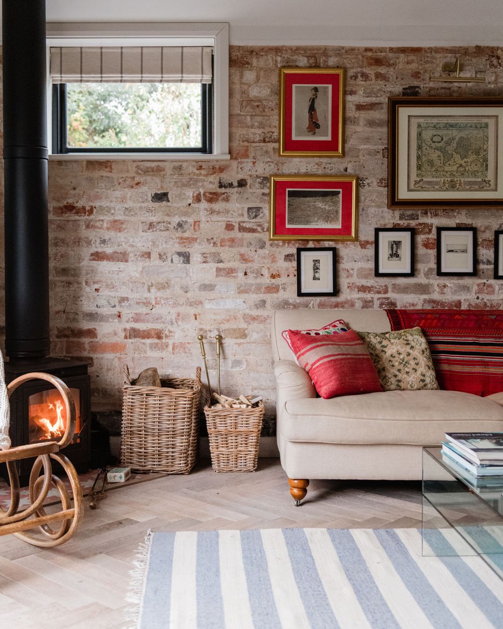 Modern living room with exposed brick walls, striped area rug, and wicker baskets showcasing rustic-industrial design.