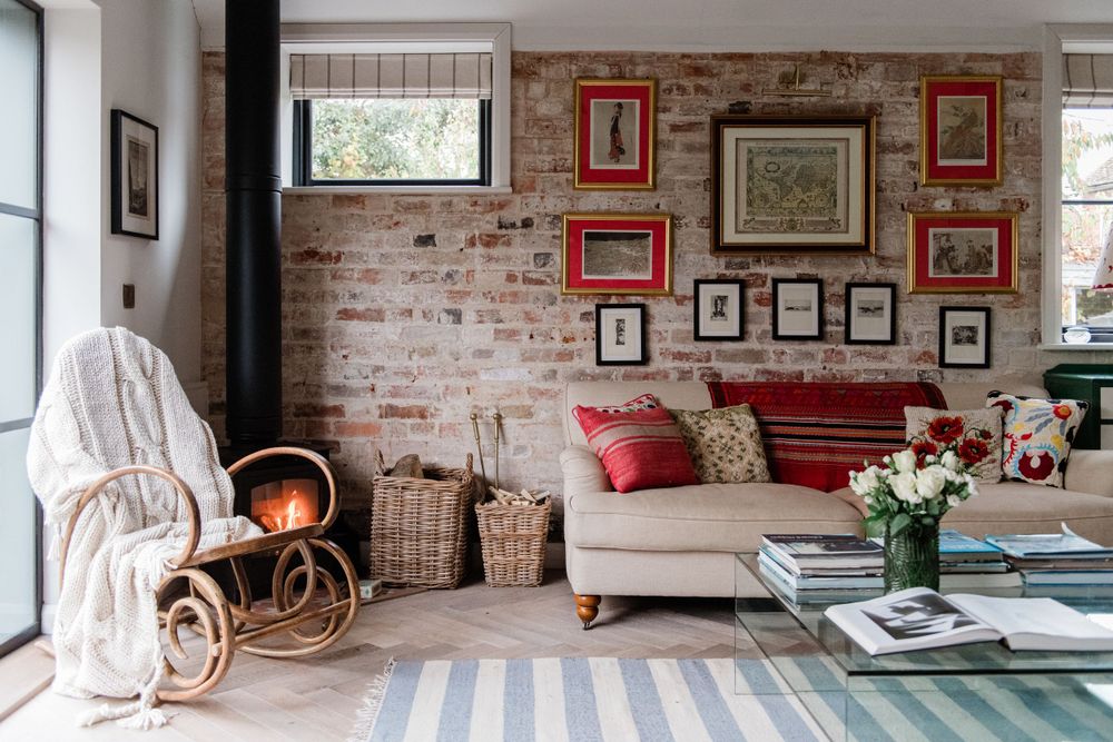 A modern rustic living room features exposed brick walls, framed artwork, and comfortable seating with natural lighting.