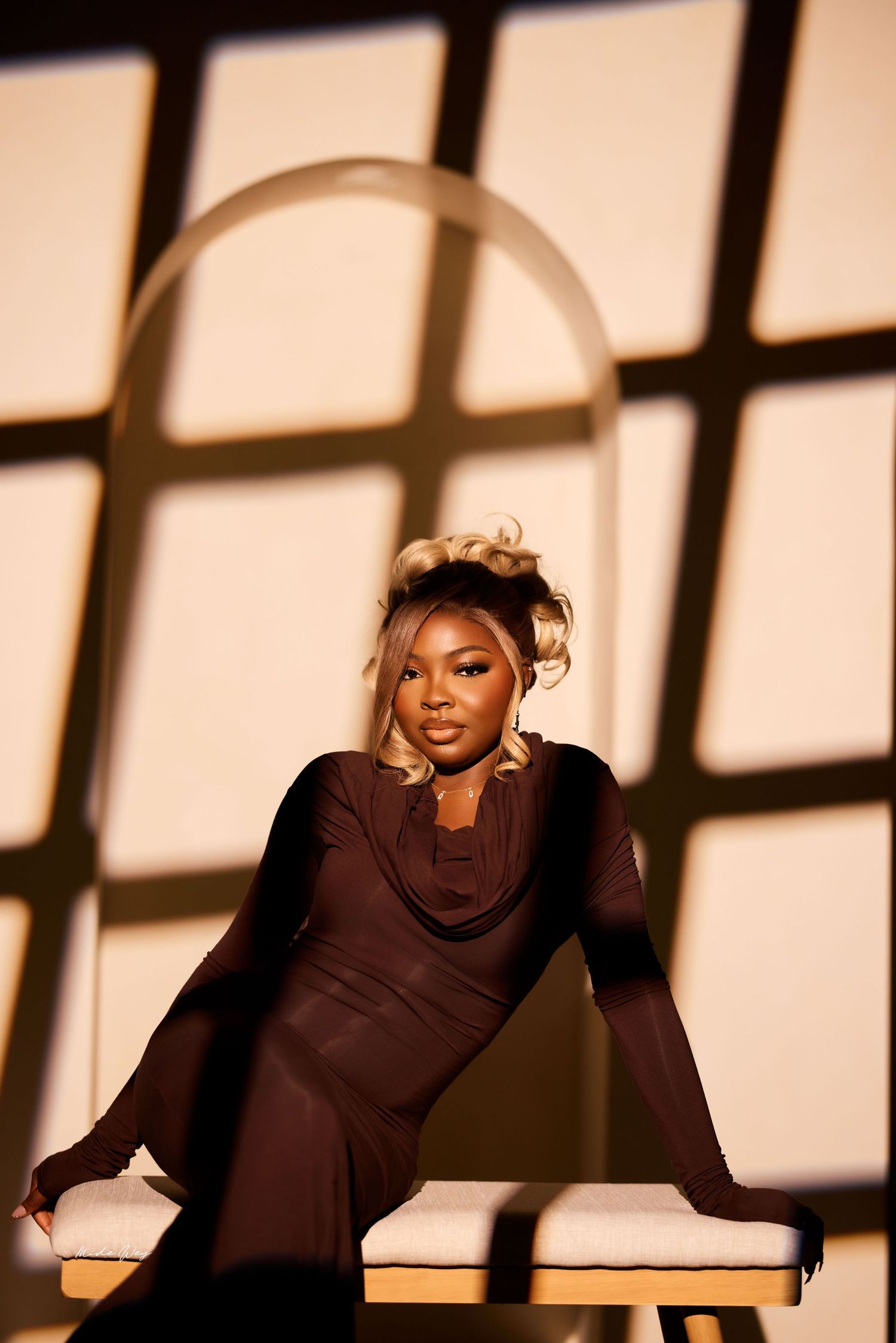 A dancer in black attire performs an expressive contemporary dance sequence against a backdrop of dramatic window shadows.