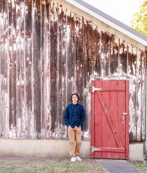 A rustic barn with peeling white paint and red doors creates a charming backdrop for outdoor portraits.