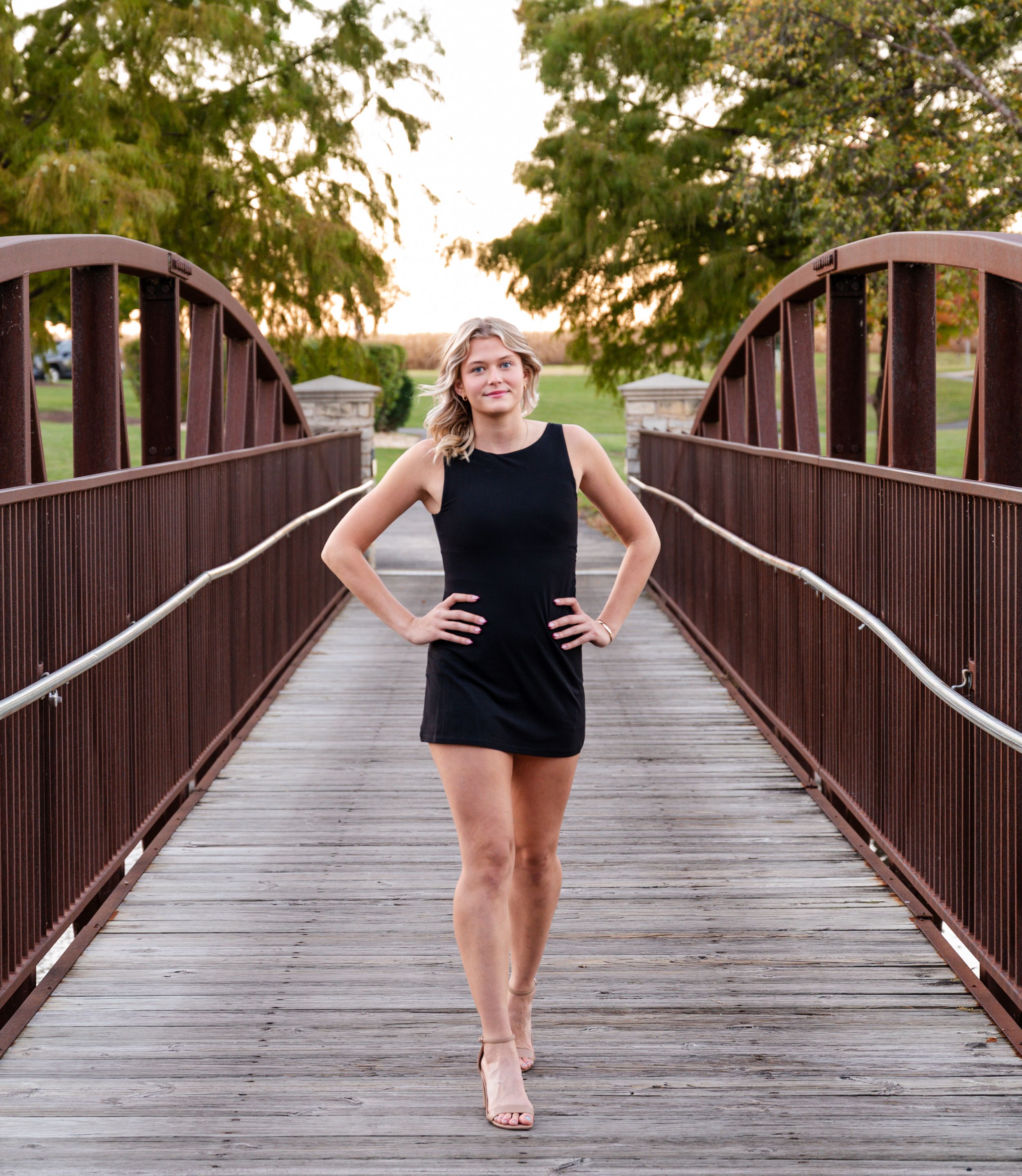 A sequence of dance poses performed on a wooden bridge walkway at sunset.