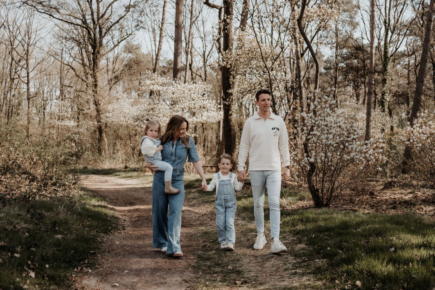 Papa en mama zitten samen met hun twee dochters op een kleedje en kijken elkaar liefdevol aan