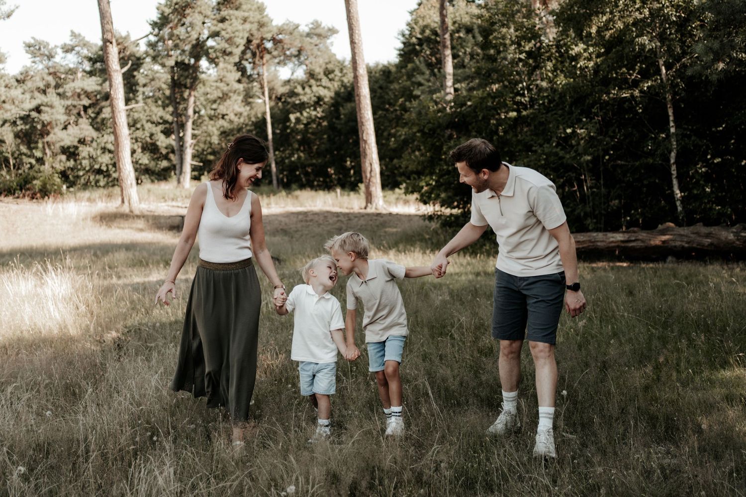 Papa en mama zitten samen met hun twee dochters op een kleedje en kijken elkaar liefdevol aan