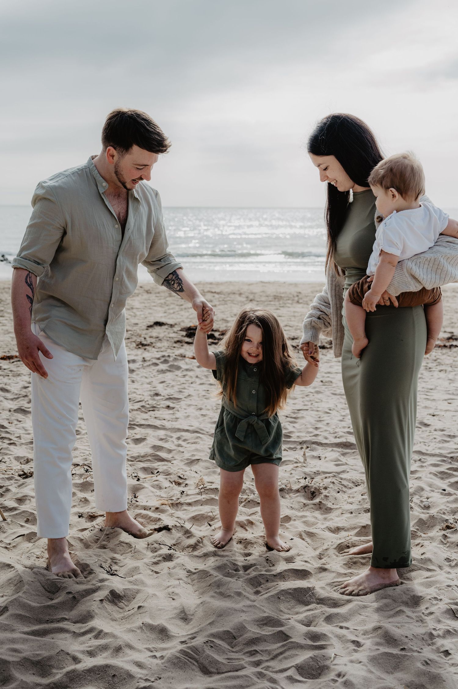 Family enjoying a playful moment together on a cloudy beach.
