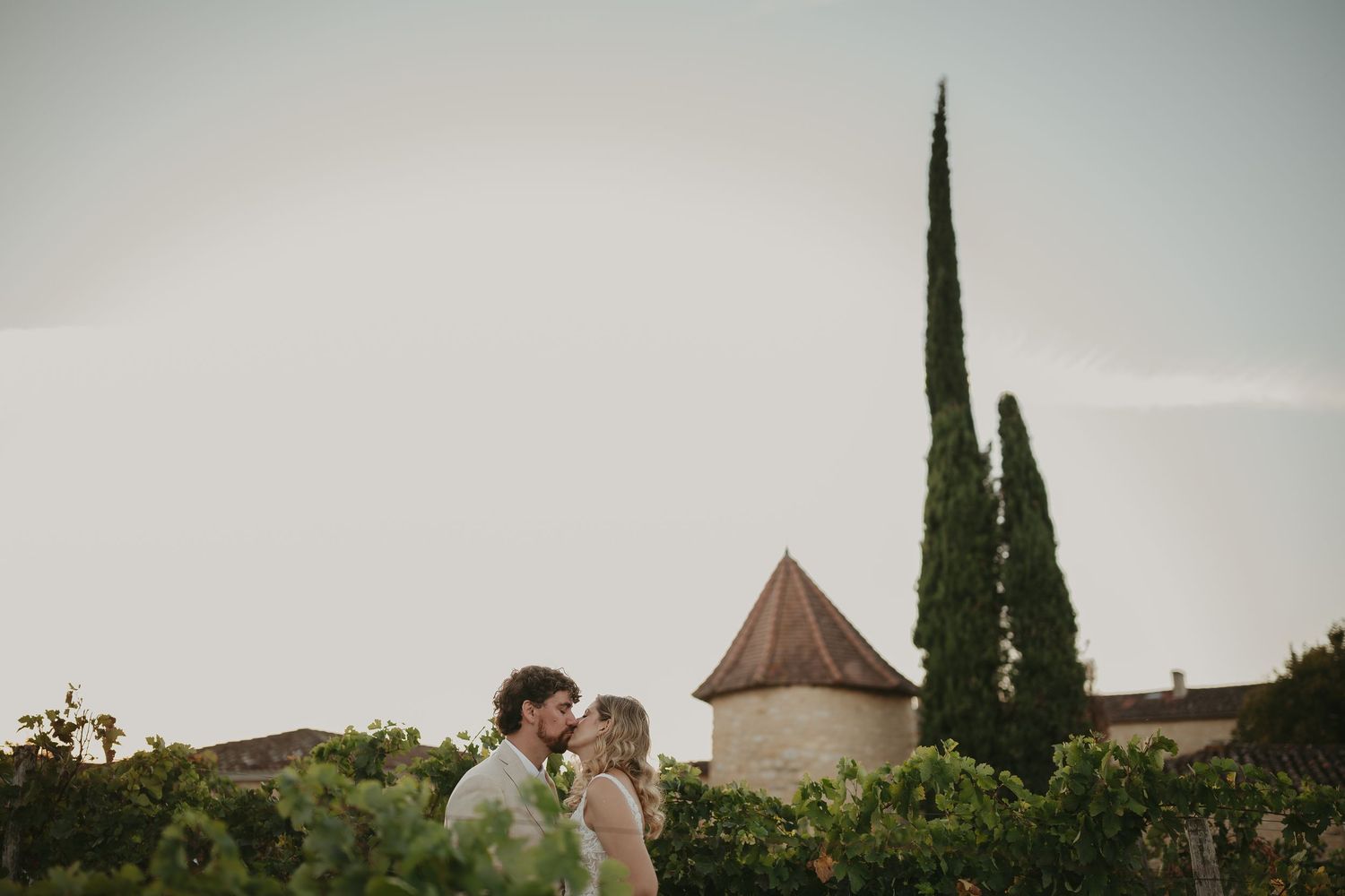 Couple sur le point de s'embrasser dans les vignes, une tour en pierre et des cyprès en arrière-plan