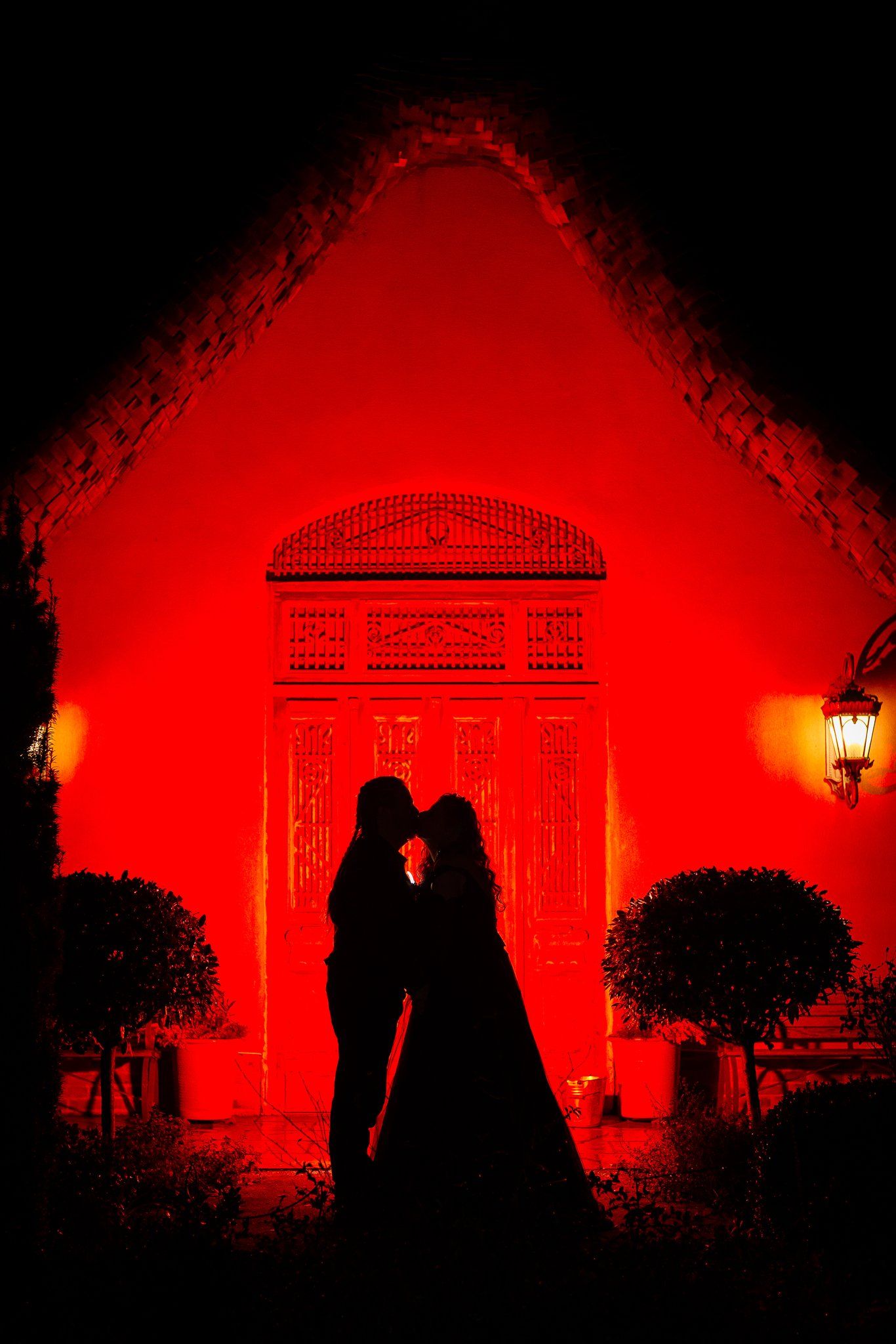 Silhouette of a bride and groom against a red-lit doorway at Le Petit Chateau, Otterburn, on Halloween night