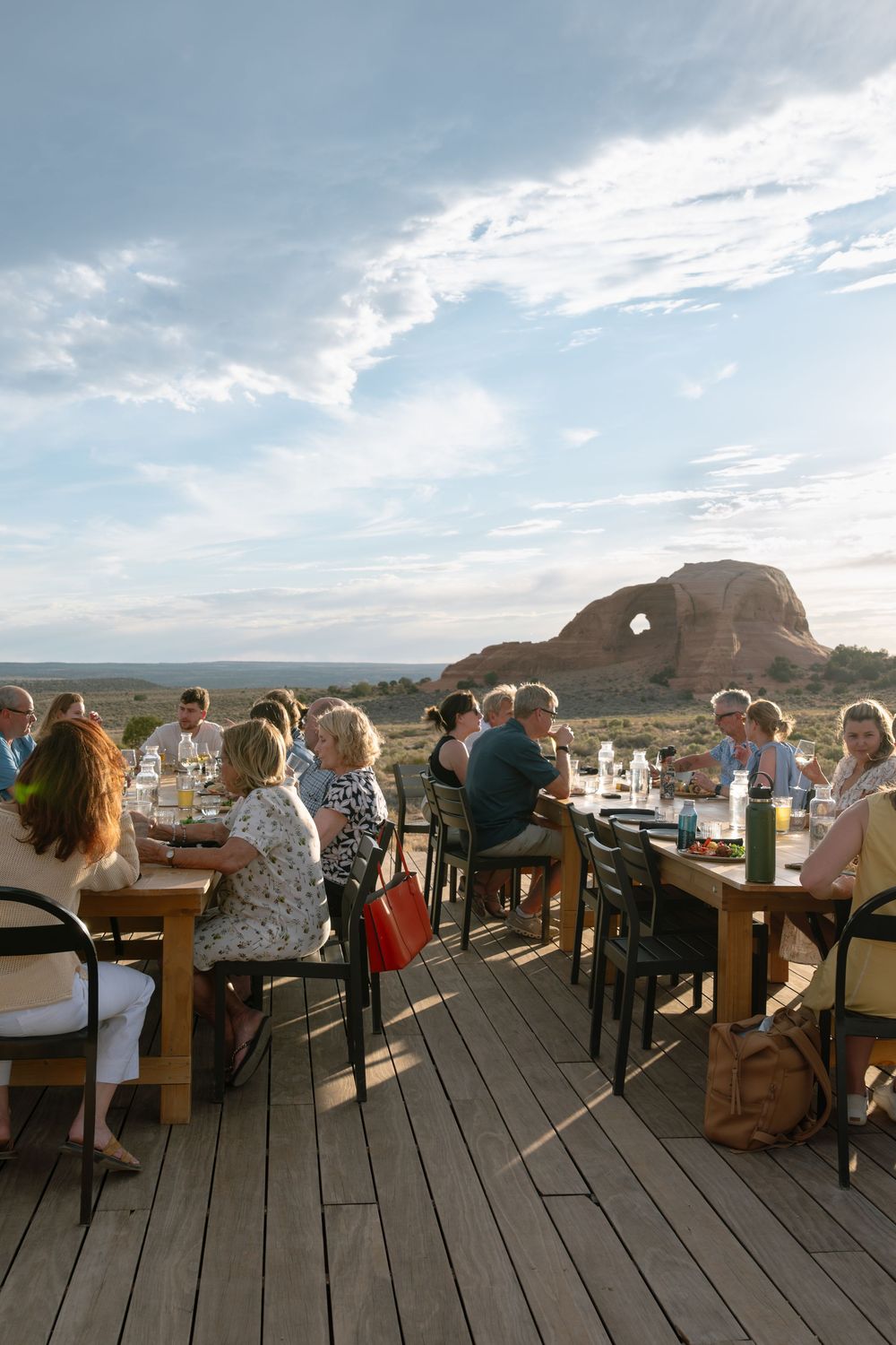 Outdoor dining on a wooden deck with scenic red rock desert landscape and blue sky in the background.