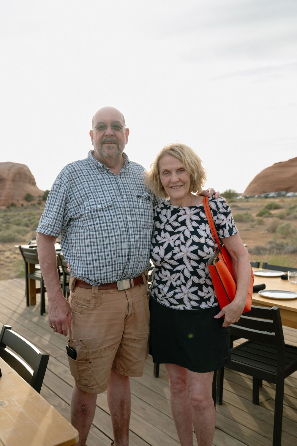 Couple posing together on outdoor deck with red rock formations in background at desert restaurant.