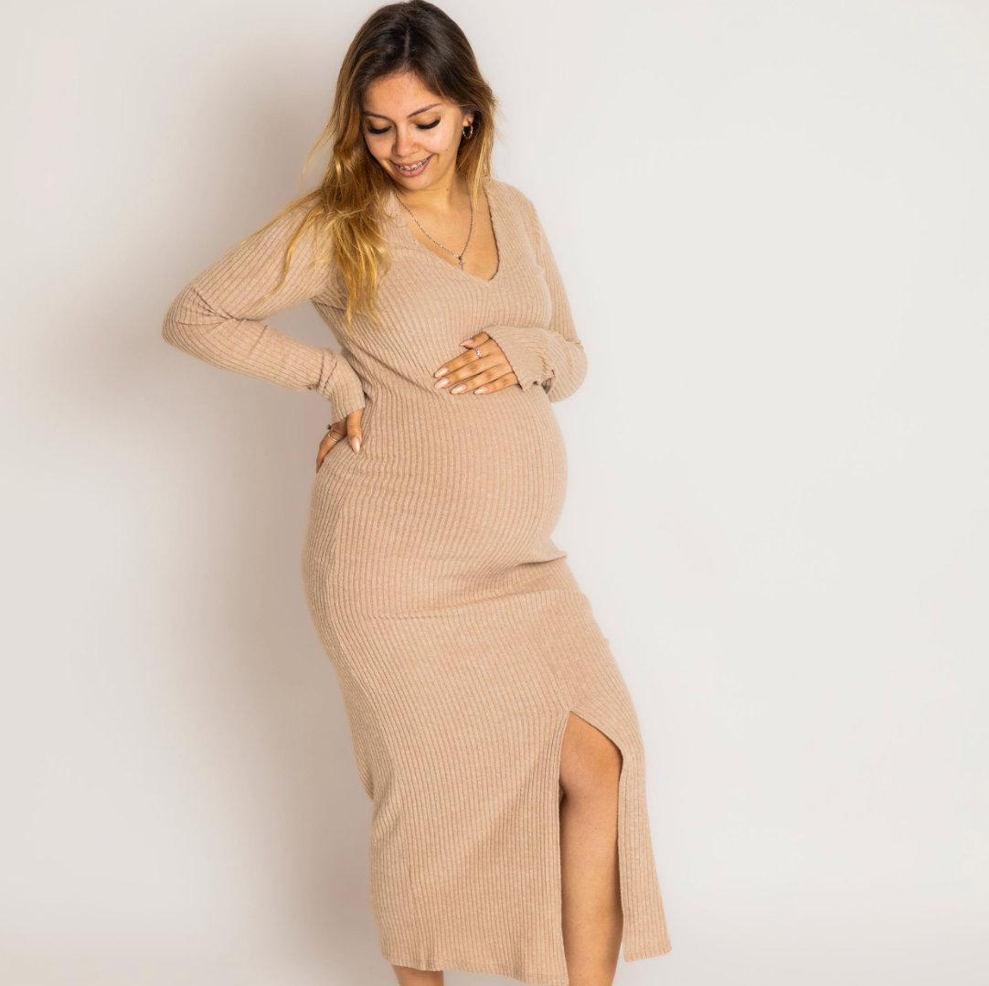 Pregnant woman wearing a beige ribbed knit wrap maternity dress with long sleeves and side slit.