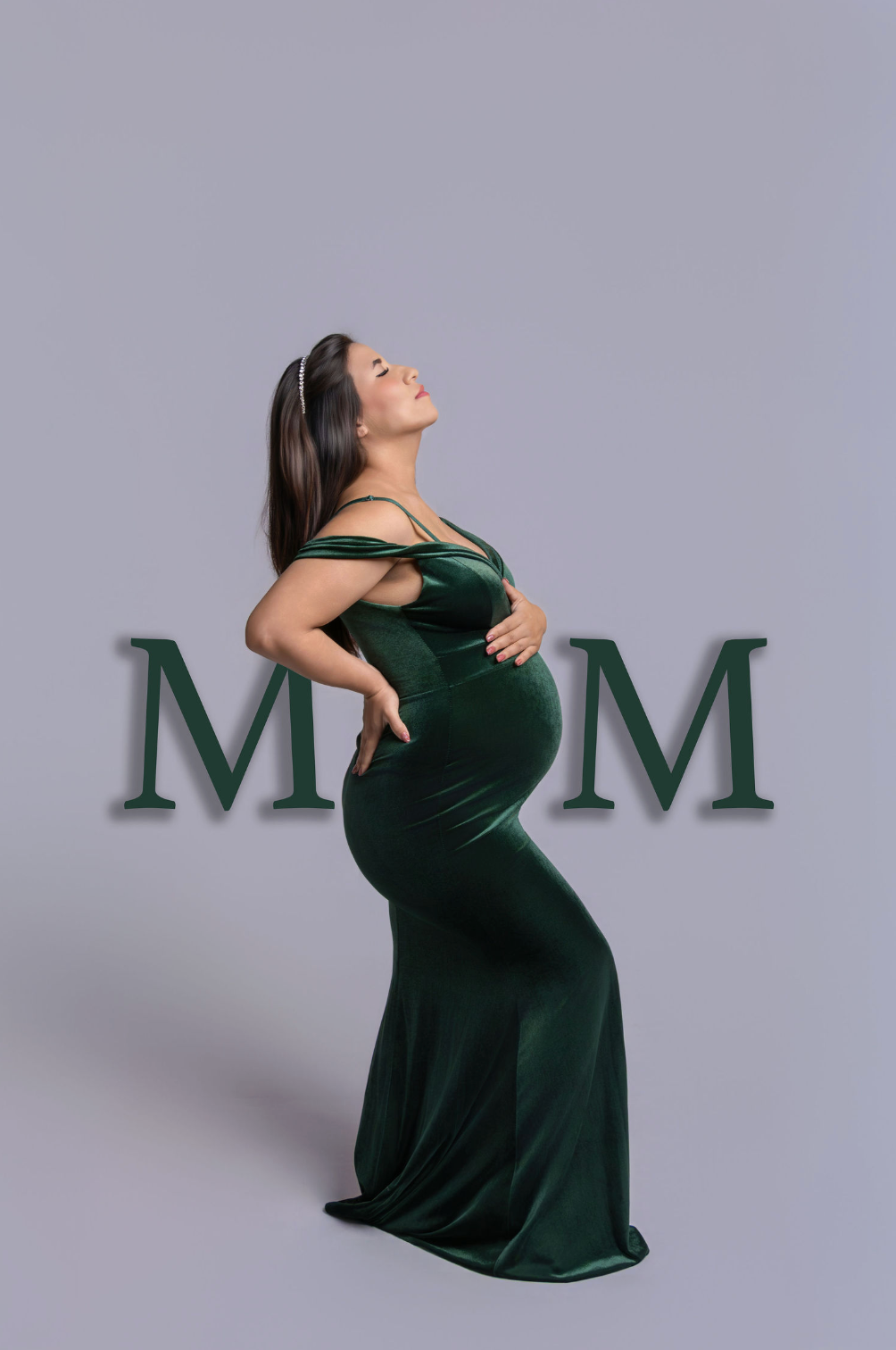 Pregnant woman in elegant green velvet gown posing gracefully with MOM text overlay on gray background.