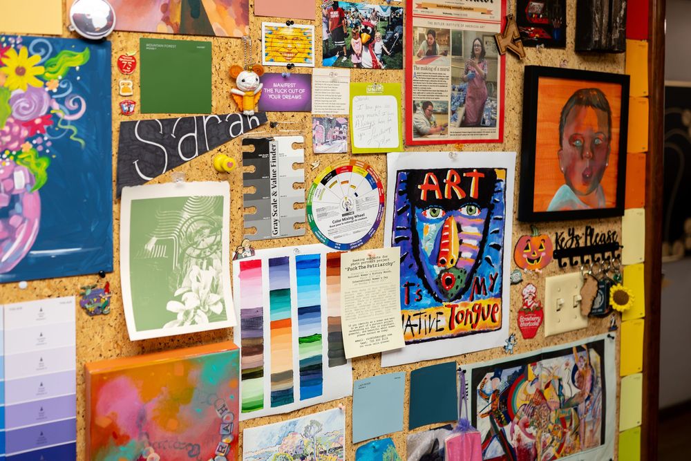 Colorful bulletin board displaying student artwork, paintings, and art class projects in a creative classroom setting.