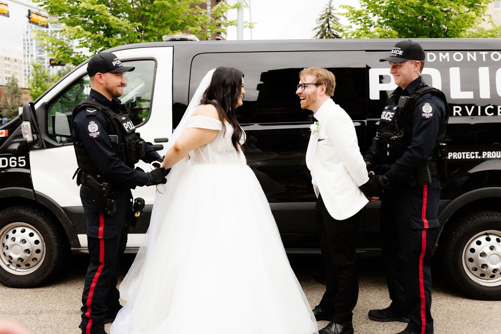 Bride and groom posing with two Edmonton Police Service officers in front of a police van on their wedding day.