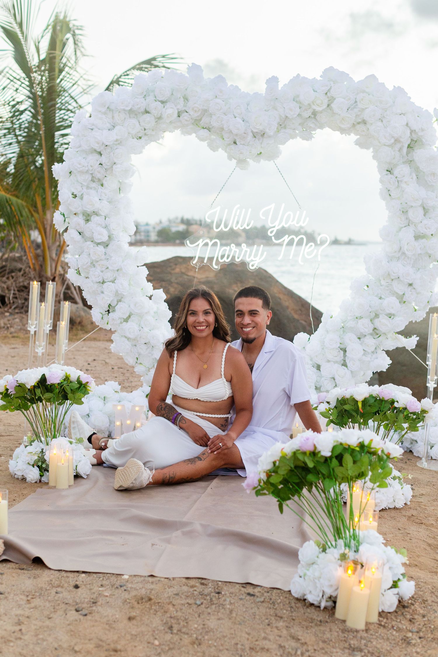 Marriage proposal. Man, woman, and decorative setup with white flower heart overlooking the ocean in Río Grande, Puerto Rico.